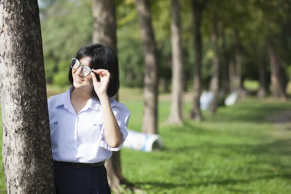 Chica de pie y sonriendo cerca de un árbol . — Foto de Stock