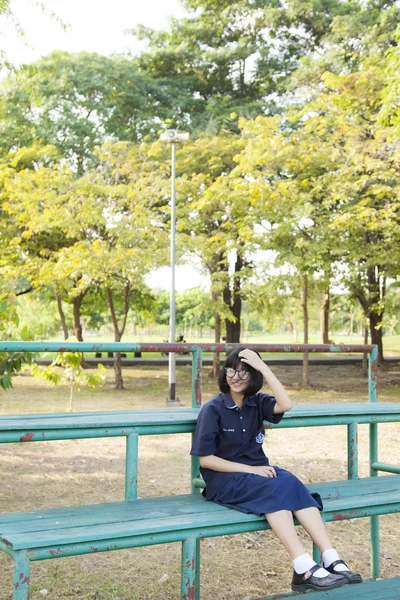 Mädchen mit Brille sitzt auf der Bank. — Stockfoto