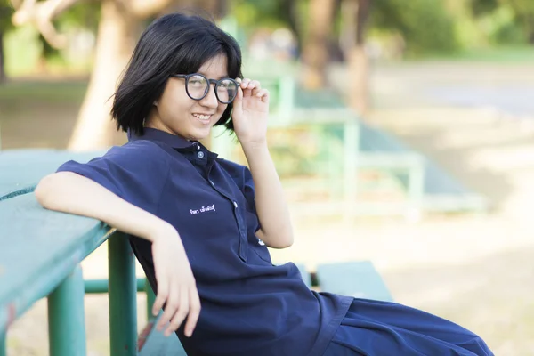 Meisje dragen van een bril zittend op de Bank. — Stockfoto