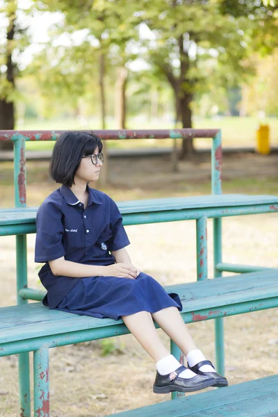Dziewczyna w okularach siedzący na ławce. — Zdjęcie stockowe