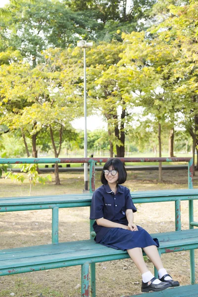 Chica con gafas sentada en el banco . — Foto de Stock