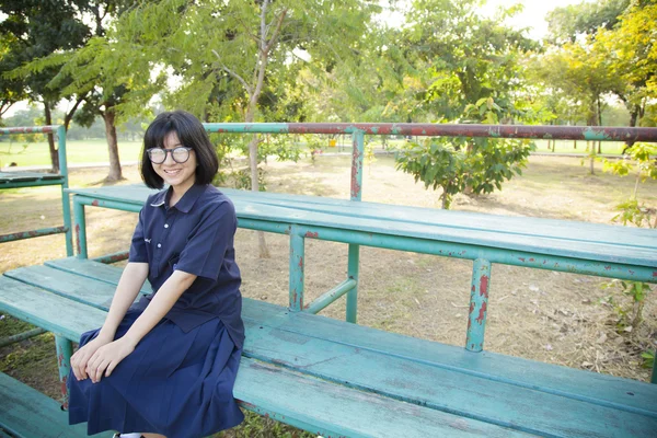 Ragazza con gli occhiali seduta sulla panchina . — Foto Stock