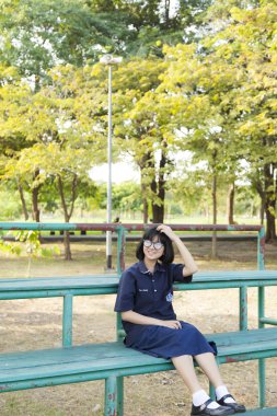 Bankta oturan gözlüklü kız.