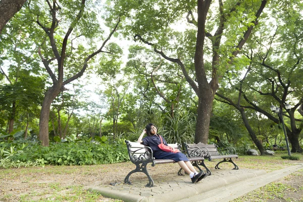 Flickan bär glasögon som sitter på bänken. — Stockfoto