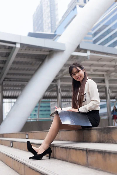 Happy businesswoman sitting on sidewalk. — Stock Photo, Image