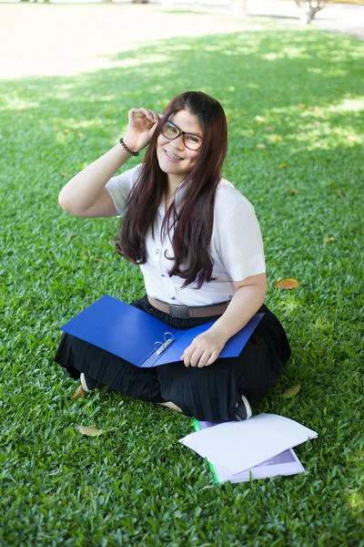 Çimenlerin üzerine oturmuş kız öğrenci — Stok fotoğraf