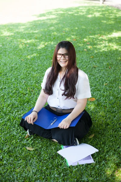 Çimenlerin üzerine oturmuş kız öğrenci — Stok fotoğraf