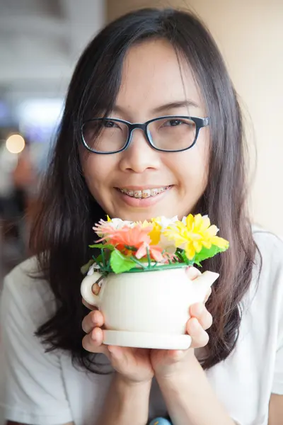 Asya kadın tutun pot çiçek. — Stok fotoğraf