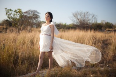 Gelin bir çayırda ayakta.