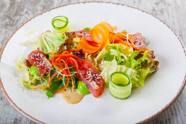 Ton balıklı salata, salatalık, havuç, dolma biber ve sos.