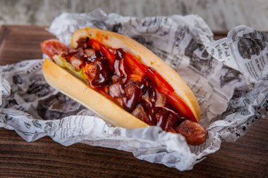 Sosisli, pastırmalı, domatesli ve baharatlı domates soslu sosisli sandviç.