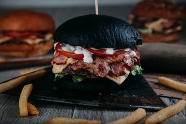 Tahtanın üzerinde baltayla etli siyah hamburger.