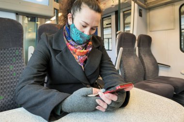 İngiltere 'deki trende kapalı bir şekilde yüzün maskesini takan kadın yolcu.