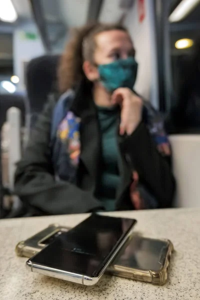 Kvinnlig passagerare bär ansikte täcka mask under covid-19 lockdown laddning smartphone inne tåg i england uk — Stockfoto