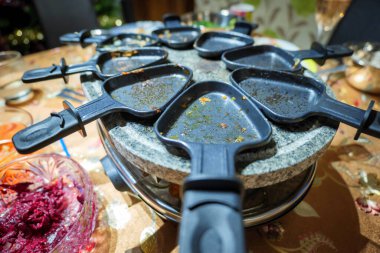 Aile yemeği masası Raclette yemeği paylaşır.