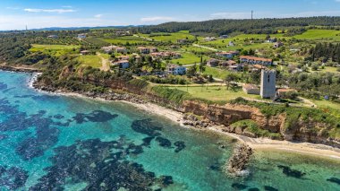 View of the Byzantine Tower of Saint Paul in Nea Fokaia, Chalkidiki, Greece, near the coast with turquoise sea and village landscape.
