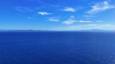 Drone view of Nea Fokaia in Chalkidiki, Greece, showing turquoise water, the harbour, fishing boats, and coastline under summer light.