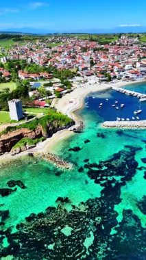 Drone view of Nea Fokaia in Chalkidiki, Greece, showing turquoise water, the harbour, fishing boats, and coastline under summer light.