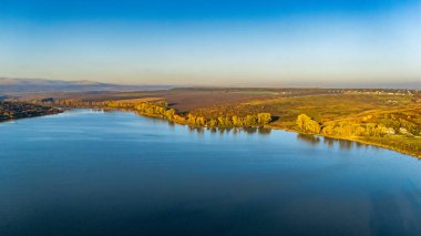 Sabahın erken saatlerinde Romanya 'nın Iasi kenti yakınlarındaki Dumbrava Gölü' nün insansız hava aracı görüntüsü. Sakin su, sis ve sonbahar renkleri huzurlu bir manzara yaratır..