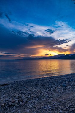 Yunanistan 'ın orta kesimindeki Korint Körfezi üzerinde gün batımı, Skaloma köyünden ele geçirildi. Sahne, altın saat boyunca renkli gökyüzü, sakin deniz ve Akdeniz kıyılarını gösteriyor. Yunanistan 'ın deniz manzarası ve seyahat manzarası.