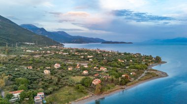 Yunanistan 'ın orta kesimindeki bir kıyı kasabası olan Marathias' ın hava aracı görüntüsü, Korint Körfezi kıyı şeridi, açık mavi deniz, geleneksel evler ve Akdeniz manzarasını gösteriyor. Manzaralı Yunan kıyıları, yaz gezileri, yüksek açılı insansız hava aracı görüntüleri.
