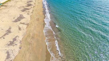 Yunanistan 'ın Chalkidiki kentindeki Kalyves Sahili' nin insansız hava aracı görüntüsü. Turkuaz su, kumlu sahil şeridi ve Akdeniz kıyısı boyunca hafif dalgalar. Ege Denizi 'nin güzelliğini gösteren Idyllic yaz manzarası.