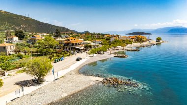 Yunanistan 'ın orta kesimindeki bir kıyı köyü olan Glyfada' nın insansız hava aracı görüntüsü, Korint Körfezi kıyı şeridi, açık mavi deniz, geleneksel evler ve Akdeniz manzarasını gösteriyor. 