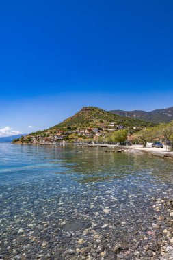 Yunanistan 'ın orta kesimindeki bir kıyı köyü olan Glyfada' nın kıyısı, Corinth Körfezi kıyı şeridi, açık mavi deniz, geleneksel evler ve Akdeniz manzarasını gösteriyor. Manzaralı Yunan kıyıları, yaz gezileri, yüksek açılı insansız hava aracı görüntüleri.