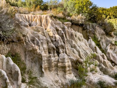 Yunanistan 'ın Chalkidiki yarımadasında Kalamitsi ile Sikia arasındaki yol kenarındaki doğal kaya oluşumları ve kil zirveleri aşındı. Akdeniz bitki örtüsü ve çalılarla çevrili, su erozyonuyla şekillenmiş engebeli jeolojik arazi..