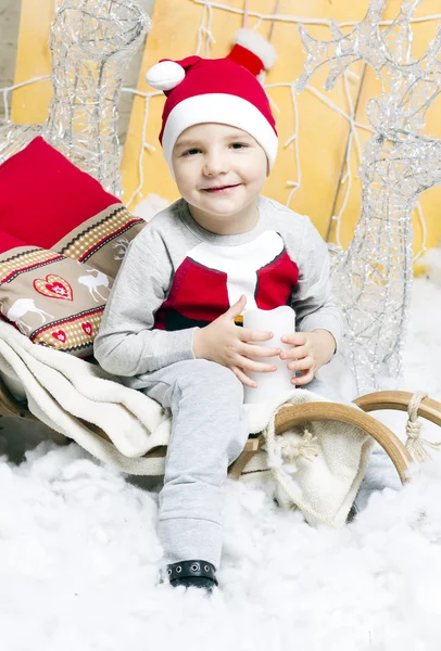 Niño en traje de Navidad sentado en un árbol de Navidad — Foto de Stock