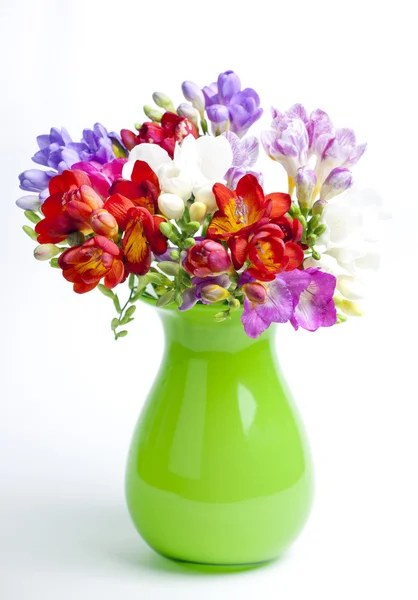 Beau bouquet de freesia coloré en vase vert sur un b blanc — Photo