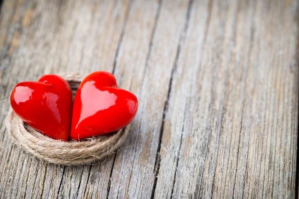 Dvě červené, ve tvaru srdce na dřevěné pozadí. — Stock fotografie