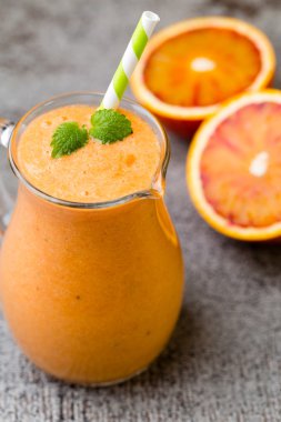 Kırmızı turuncu smoothie, gri arkaplanda..