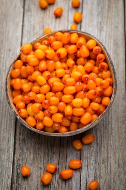 Tahta arka planda Buckthorn çilek sepeti.