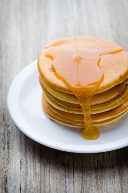 Ahşap arka planda ballı ev yapımı krep yığını.