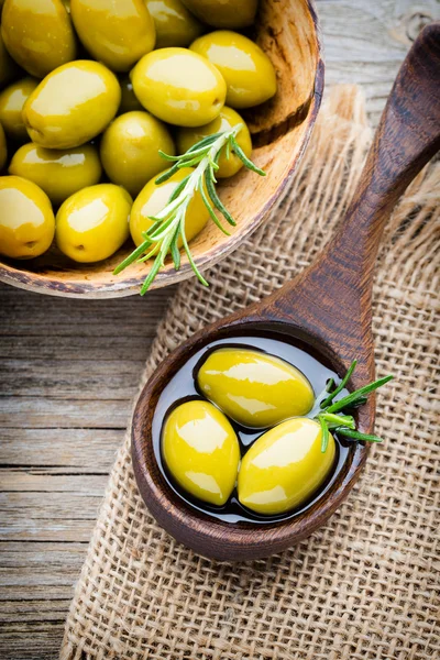 Frische Oliven und grauer Hintergrund. Oliven in Schüssel und Löffel. — Stockfoto