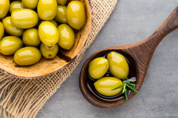 Färska oliver och grå bakgrund. Oliver i skål och sked. — Stockfoto
