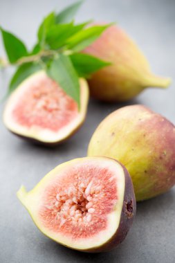 Gri bir masanın üzerinde tam bir incir ve bir incir dilimlenmiş.. 