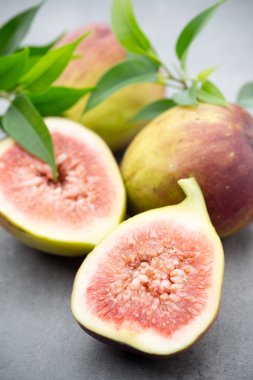 Gri bir masanın üzerinde tam bir incir ve bir incir dilimlenmiş.. 