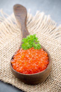 Gri arka planda kaşıkla somon havyarı.