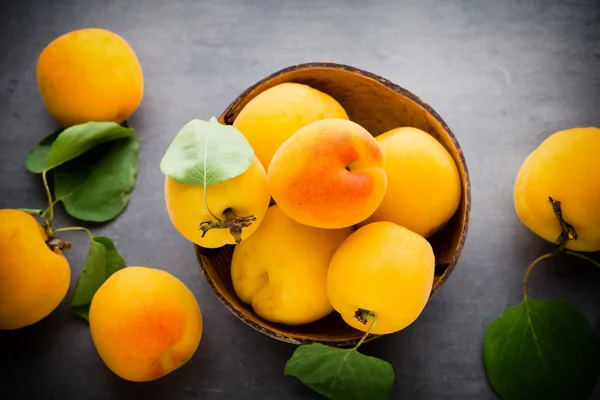 Apricots with leaves on the old wooden table. — Stock Photo, Image
