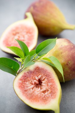 Gri bir masanın üzerinde tam bir incir ve bir incir dilimlenmiş.. 