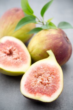 Gri bir masanın üzerinde tam bir incir ve bir incir dilimlenmiş.. 