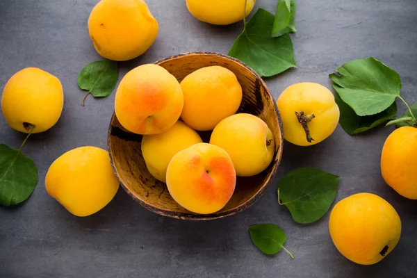 Apricots with leaves on the old wooden table. — Stock Photo, Image