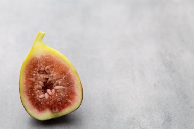 Gri bir masanın üzerinde tam bir incir ve bir incir dilimlenmiş.. 