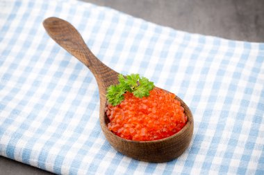 Gri arka planda kaşıkla somon havyarı.