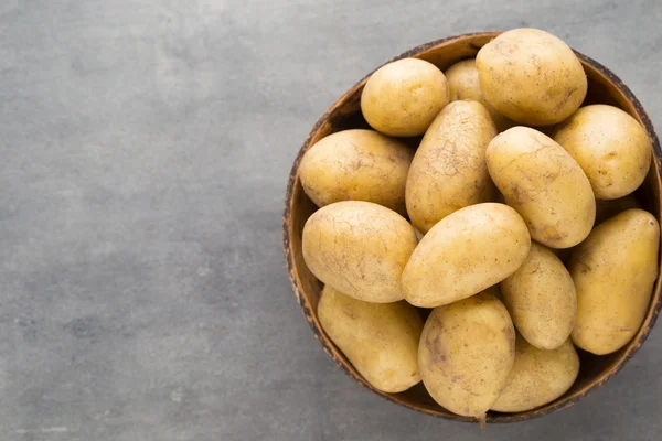 Kase, gri arka plan üzerinde yeni patates.