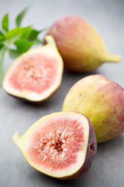 Gri bir masanın üzerinde tam bir incir ve bir incir dilimlenmiş.. 