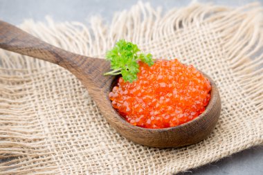 Gri arka planda kaşıkla somon havyarı.