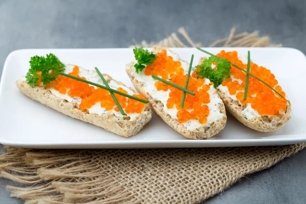 Caviar vermelho em pão em prato branco . — Fotografia de Stock